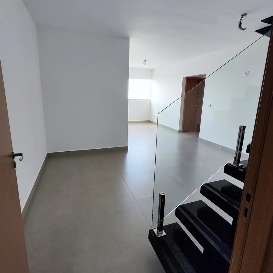 Foto real do piso de baixo de uma cobertura do Vista Reale, com a escada de granito e guarda-corpo de vidro