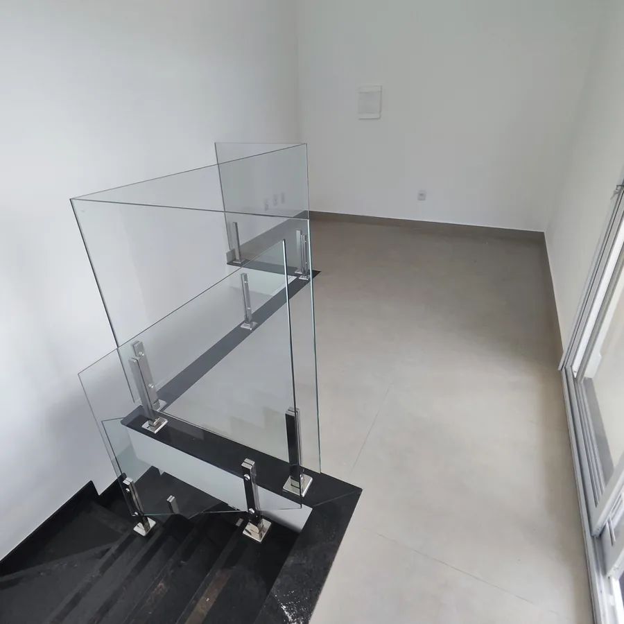 Foto real da saleta no piso de cima de uma cobertura do Vista Reale, com o guarda-corpo de vidro da escada