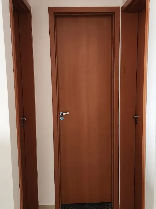 Circulação entre os quartos e o banheiro, com portas em madeira