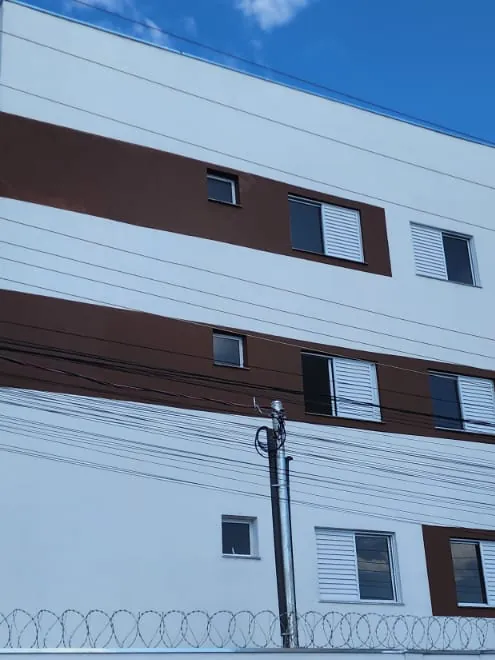Fachada do prédio, com faixas na cor madeira e cerca concertina
